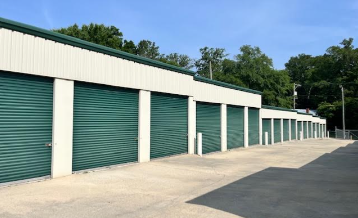 Row of drive-up storage units with green roll-up doors at an Incredible Storage facility